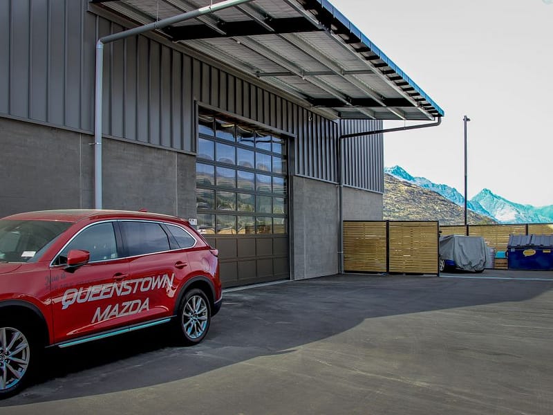 A glazed sectional industrial door installed on a grey metal building.